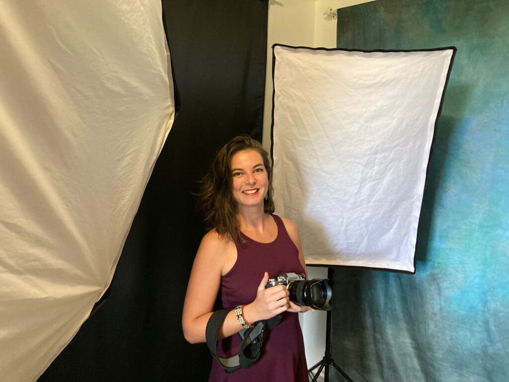 photo de camille doro tenant un appareil photo dans son studio de photographie entourée de flashs