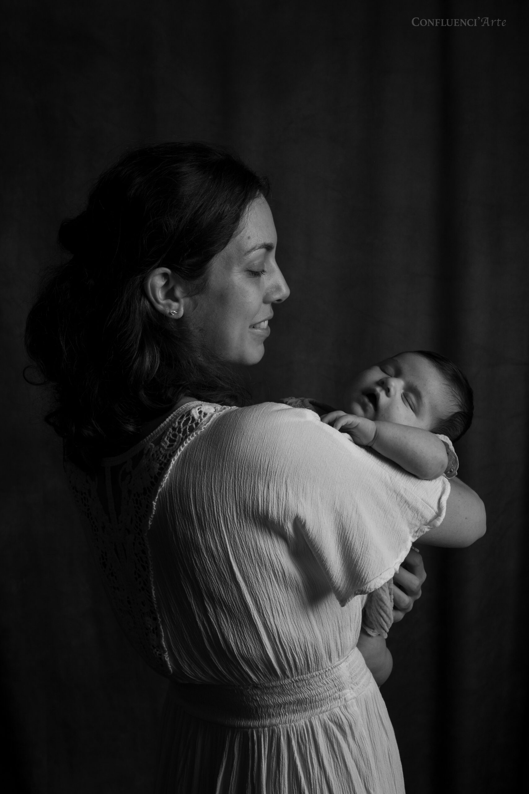 une maman de 30 ans, blanche et belle, avec son bébé fille de 3 mois qu'elle regarde avec amour lors d'une séance photo en studio à Odars