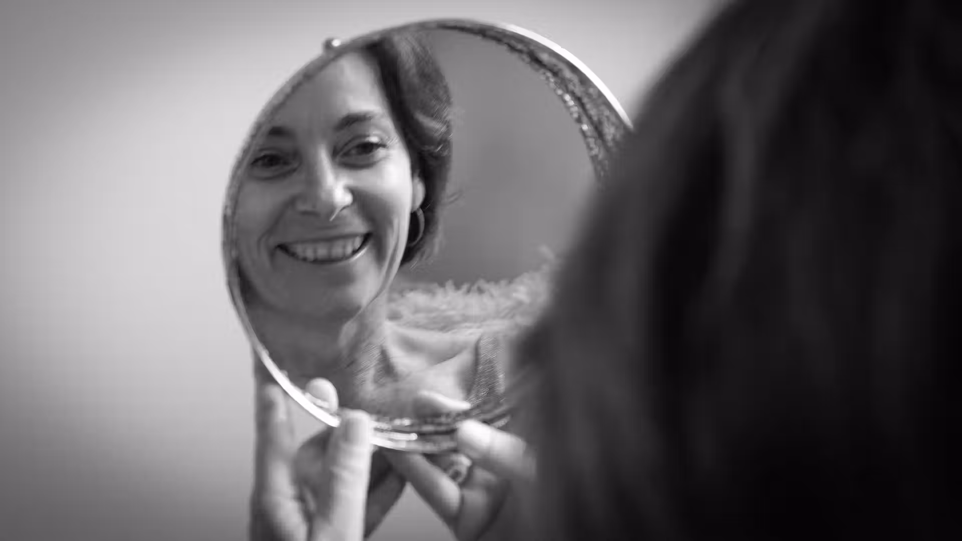 femme de 50 ans qui se regarde dans un miroir pour travailler la confiance en soi en séance photo