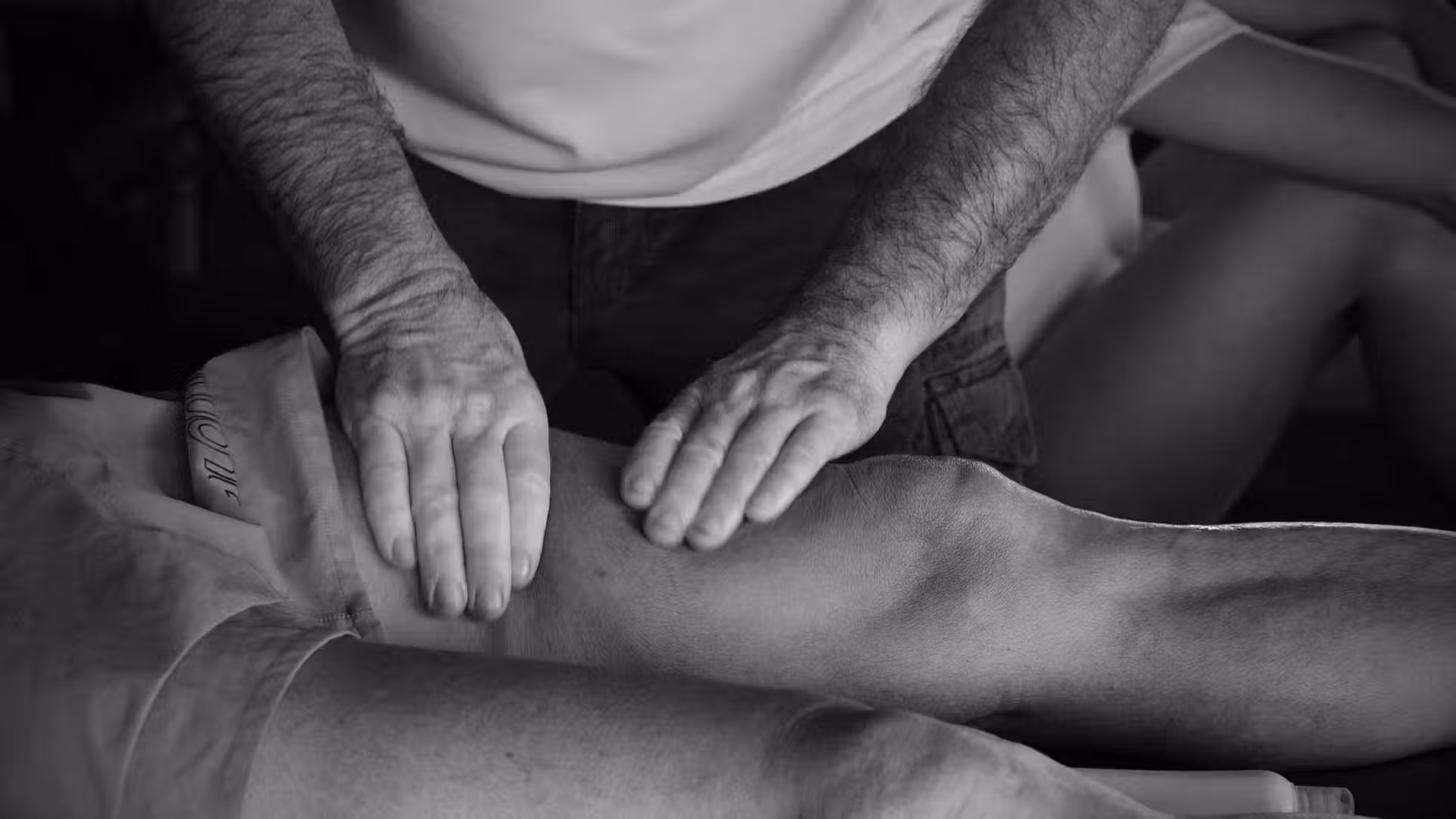 photo en noir et blanc d'un masseur osthéopathe thérapeute qui masse un client lors d'une séance photo professionnelle branding sur Toulouse
